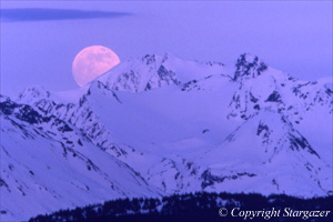 Full moon rising behind snowy mountains. Click to go to Stargazer's Photography.