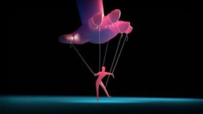 Marionette moved by strings from a giant hand.